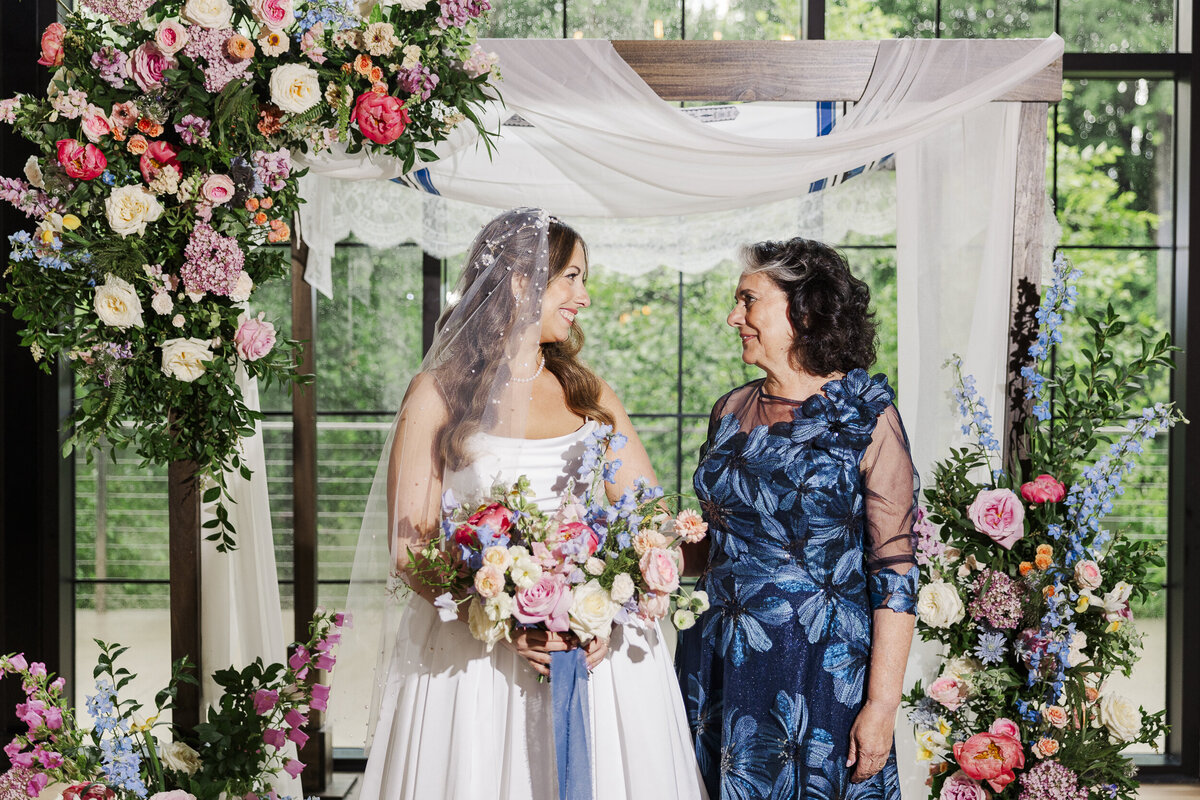 The bride and her mom take an indoor family photo at The Roundhouse in the ceremony space at their wedding