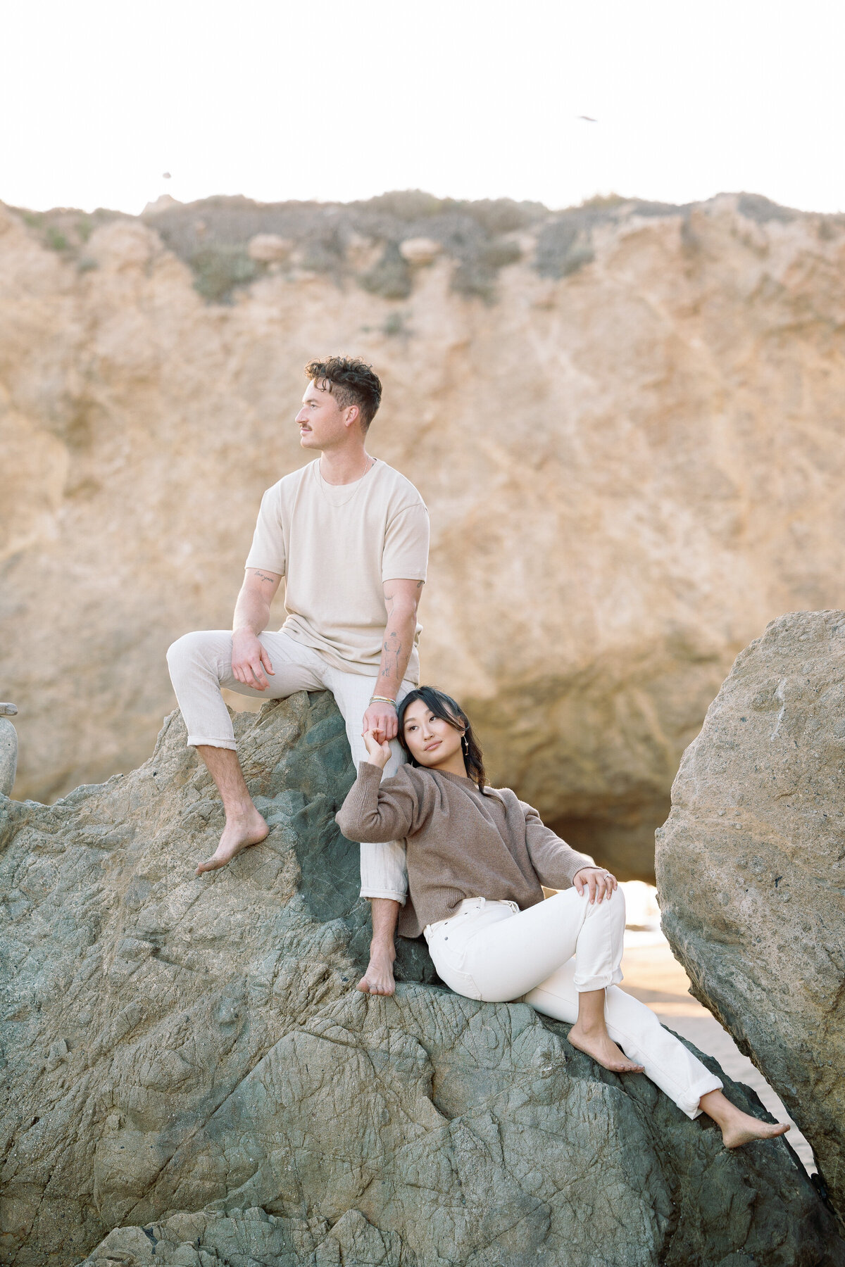 A couple sitting on rocks together holding hands