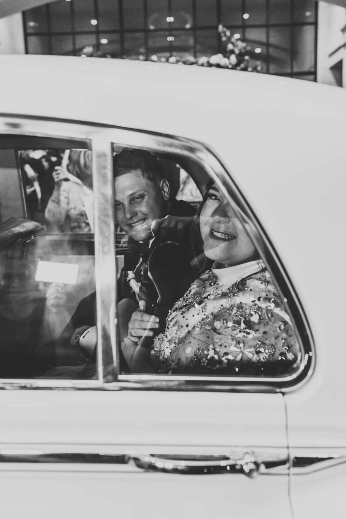 bride and groom drive off into the night in their vintage car.