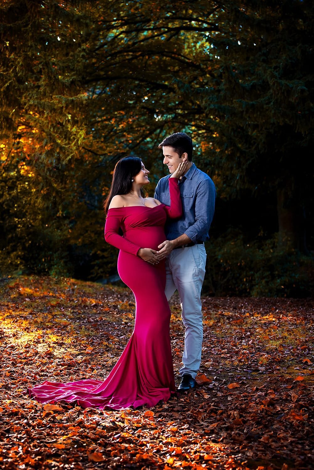 Woman in magenta maternity gown with husband at Queen Elizabeth Park in Vancouver during fall