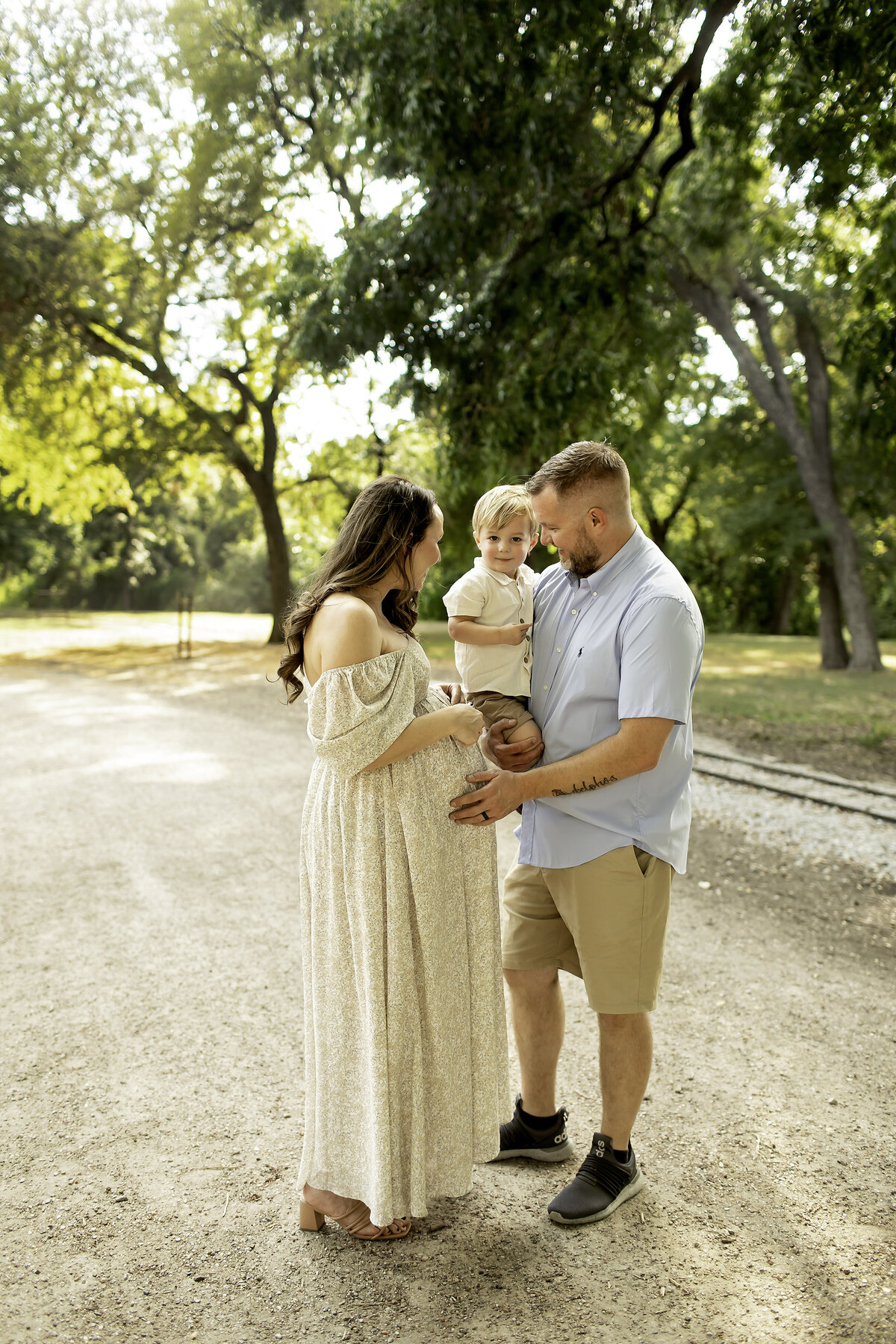 A tender maternity photo at Trinity Park, with mom and dad standing close, sharing an intimate moment as they gaze at each other, captured by Chunky Monkey Photography.