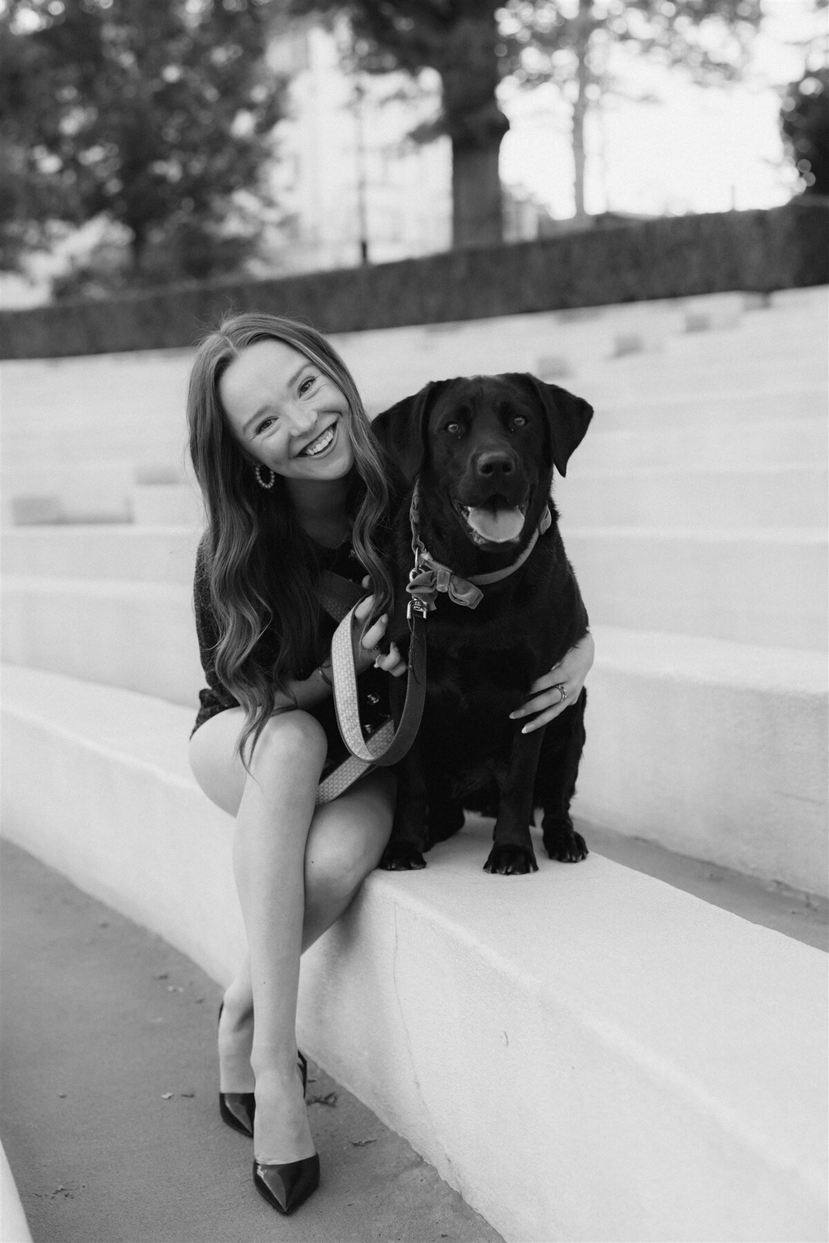 graduate girl smiling with black labrador dog