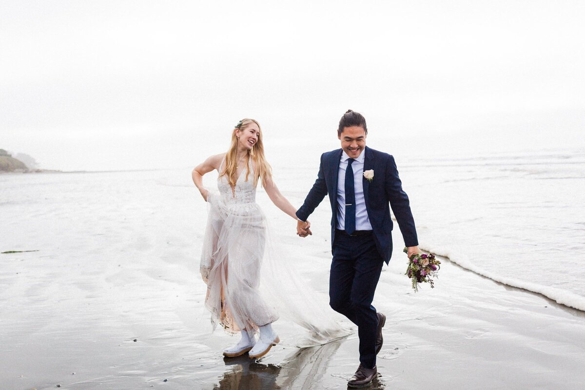 a couple who decided to elope, running from a wave a beach in Washington.