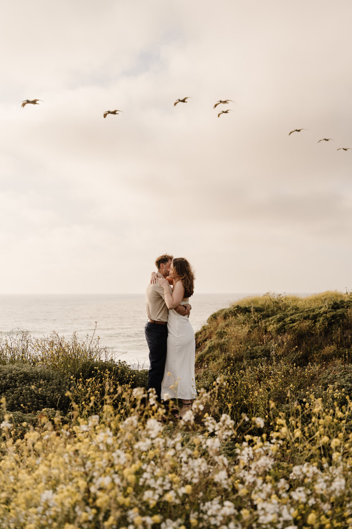 couple hugs on coastline in half moon bay
