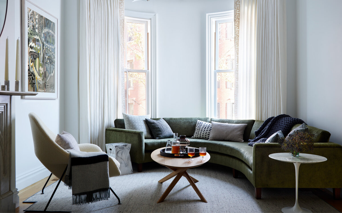 Sarah Scales, Boston designer, crafted this timeless living room in a historic brownstone. Features a custom velvet sofa, mid-century Saarinen table, Womb chair, and linen drapes with Greek fret trim.