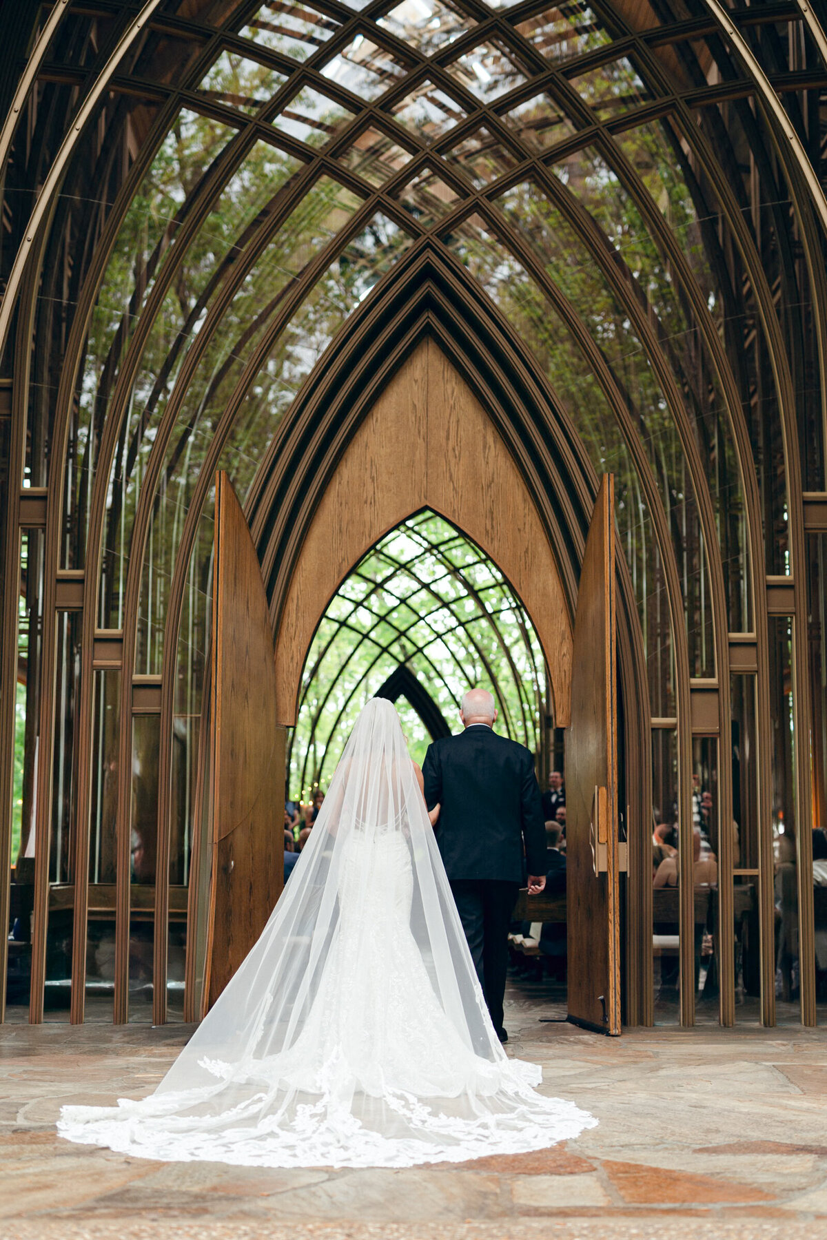 A wedding day photo of the bride and her father under umbrellas at Mildred B Cooper Chapel in Betonville Arkansas