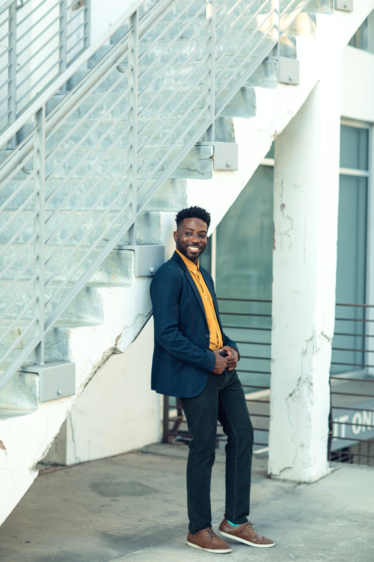 Portrait Photo Of Young Black Man Leaning Against a Staircase Smiling Los Angeles