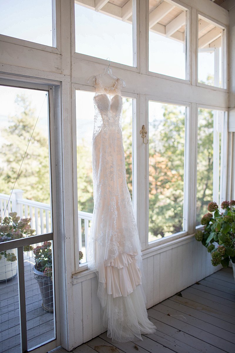 Lace wedding dress hanging in outdoor porch