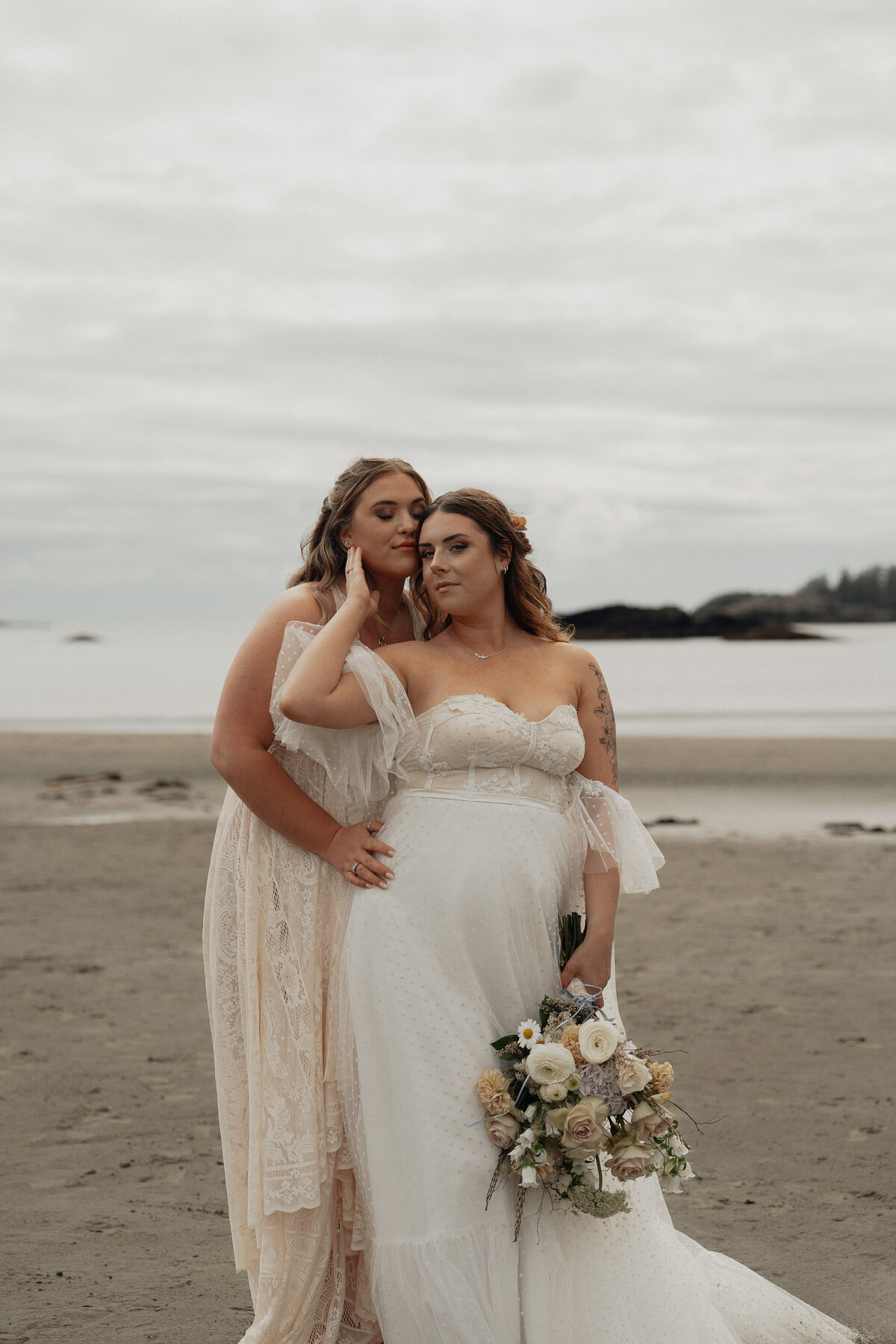 Two brides during their wedding photos on Mackenzie beach in tofino by latitude 49 photography