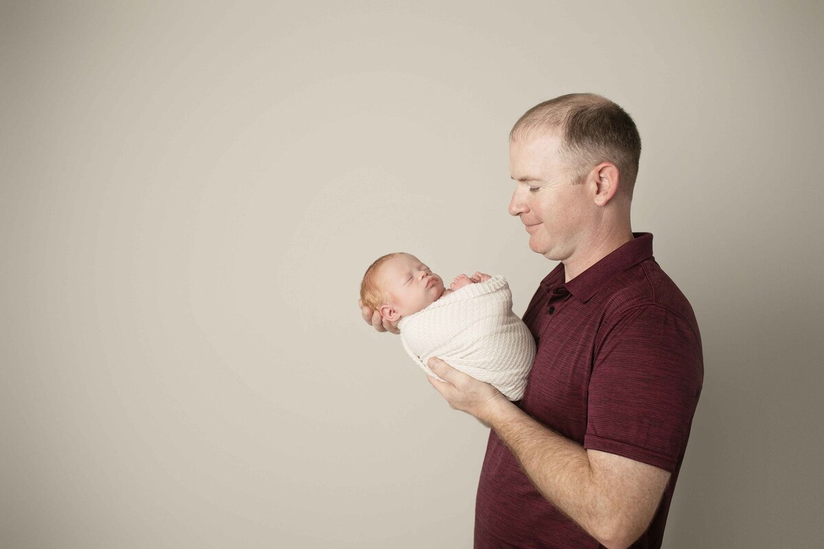 ew father gently holding his newborn son, both looking relaxed and content