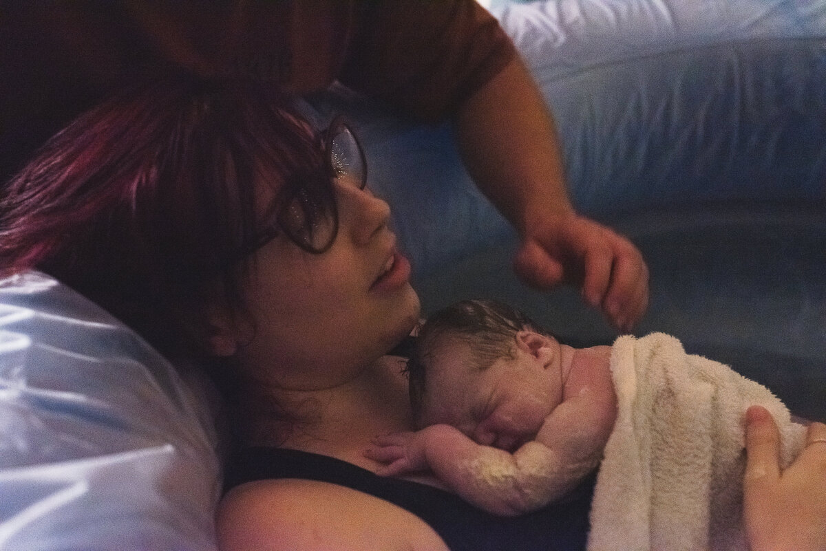 Mom after birth holding her baby after unmedicated birth at home