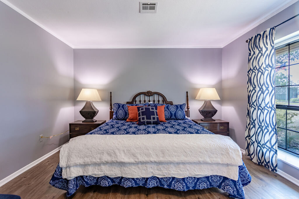 Bedroom with beautiful bedding and natural light in this 5-bedroom, 4-bathroom vacation rental house for 16+ guests with pool, free wifi, guesthouse and game room just 20 minutes away from downtown Waco, TX.