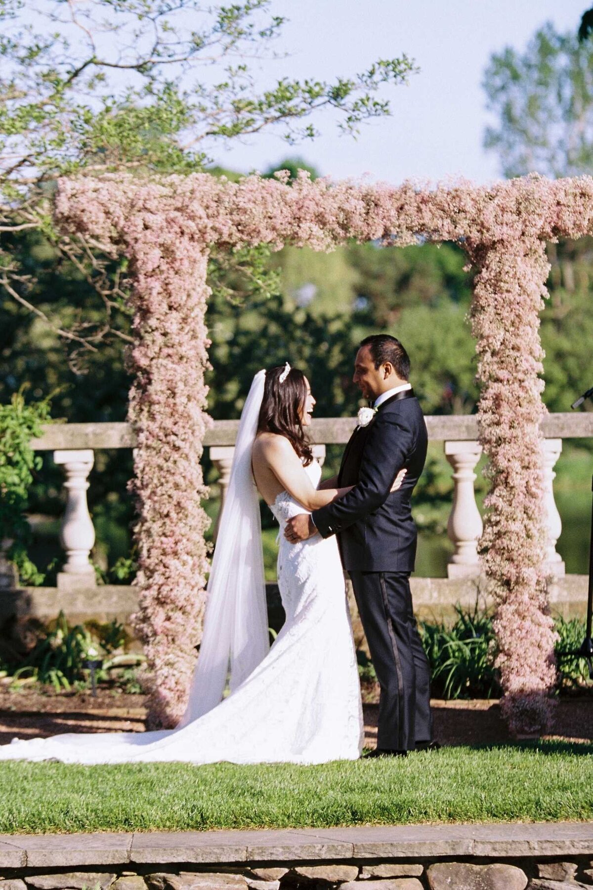Ceremony Kiss under Pink Floral Ceremony Arch at Luxury Chicago North Shore Garden Wedding Venue