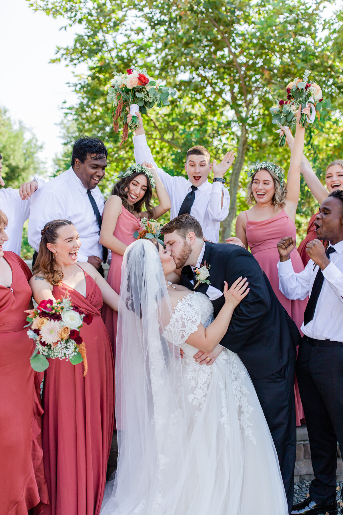 bridal party cheers bride and groom kissing