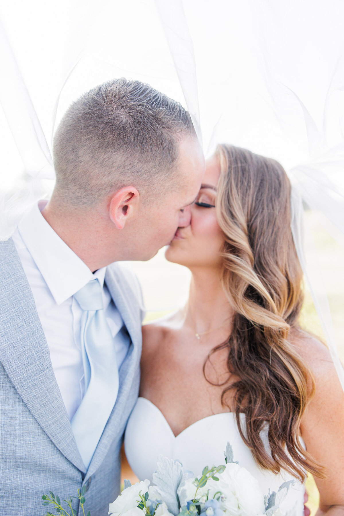 Bride and groom kissing underneath a veil representing a romantic Boston wedding photographer