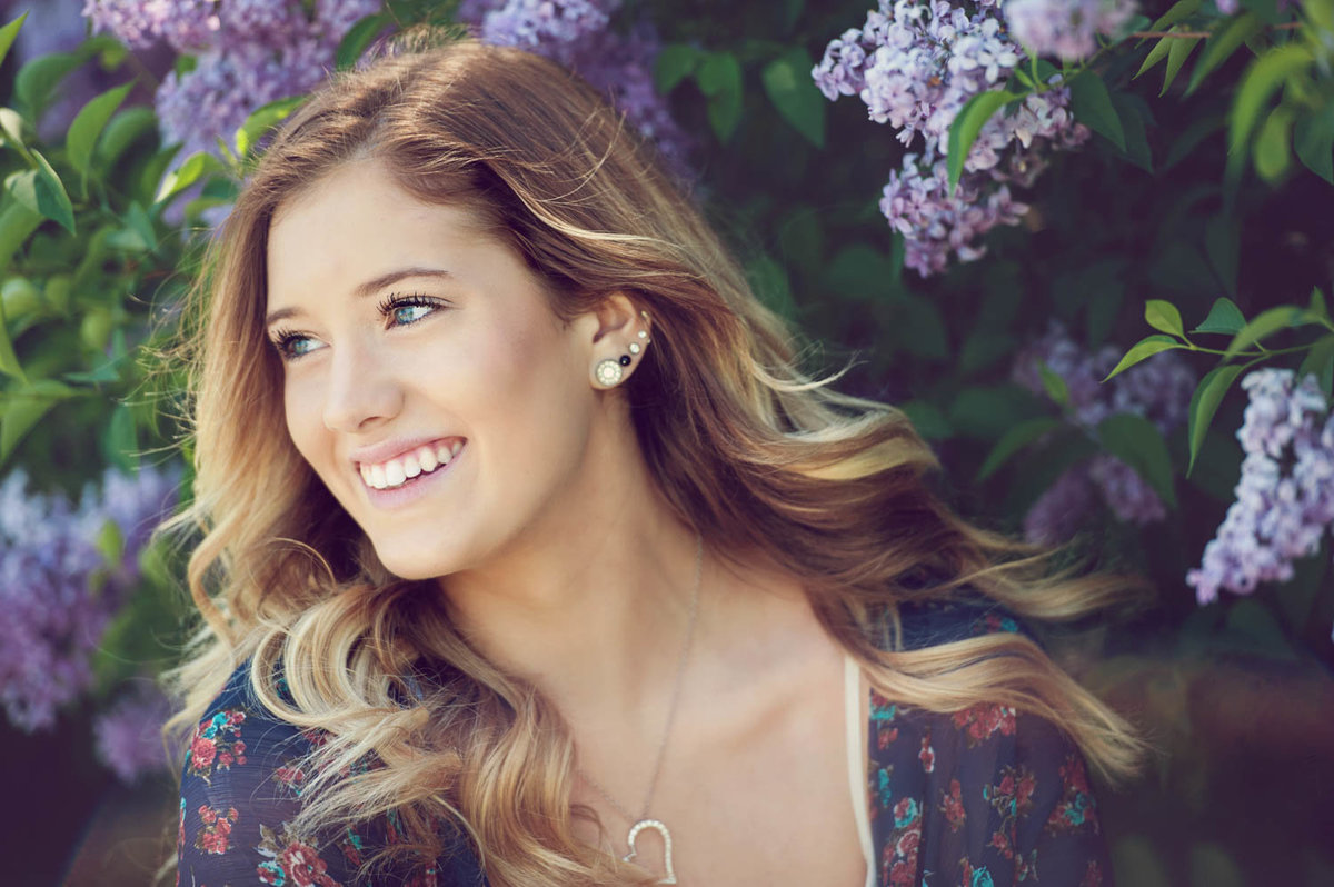 high school senior photo of girl in floral dress with lilac blooms in spring