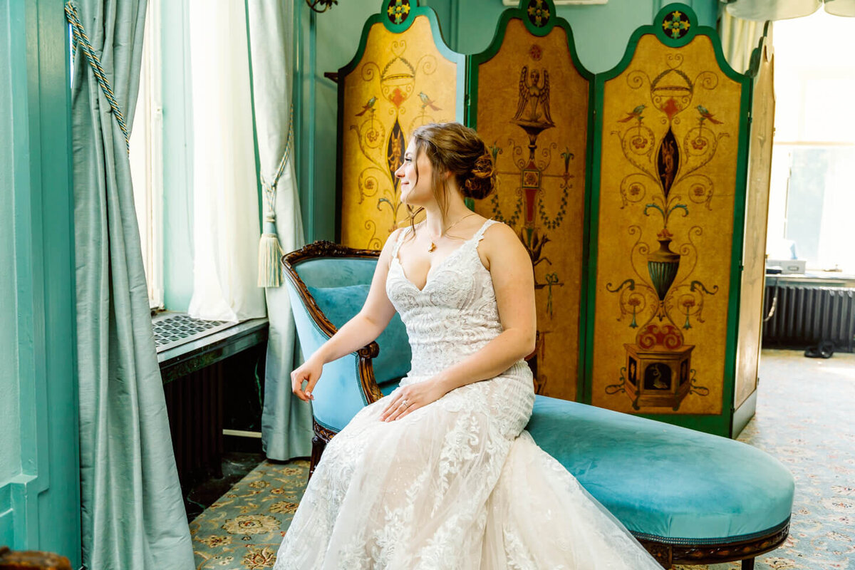 Bride posing on an antique settee in the bridal suite at the wedding venue in Dayton, OH.