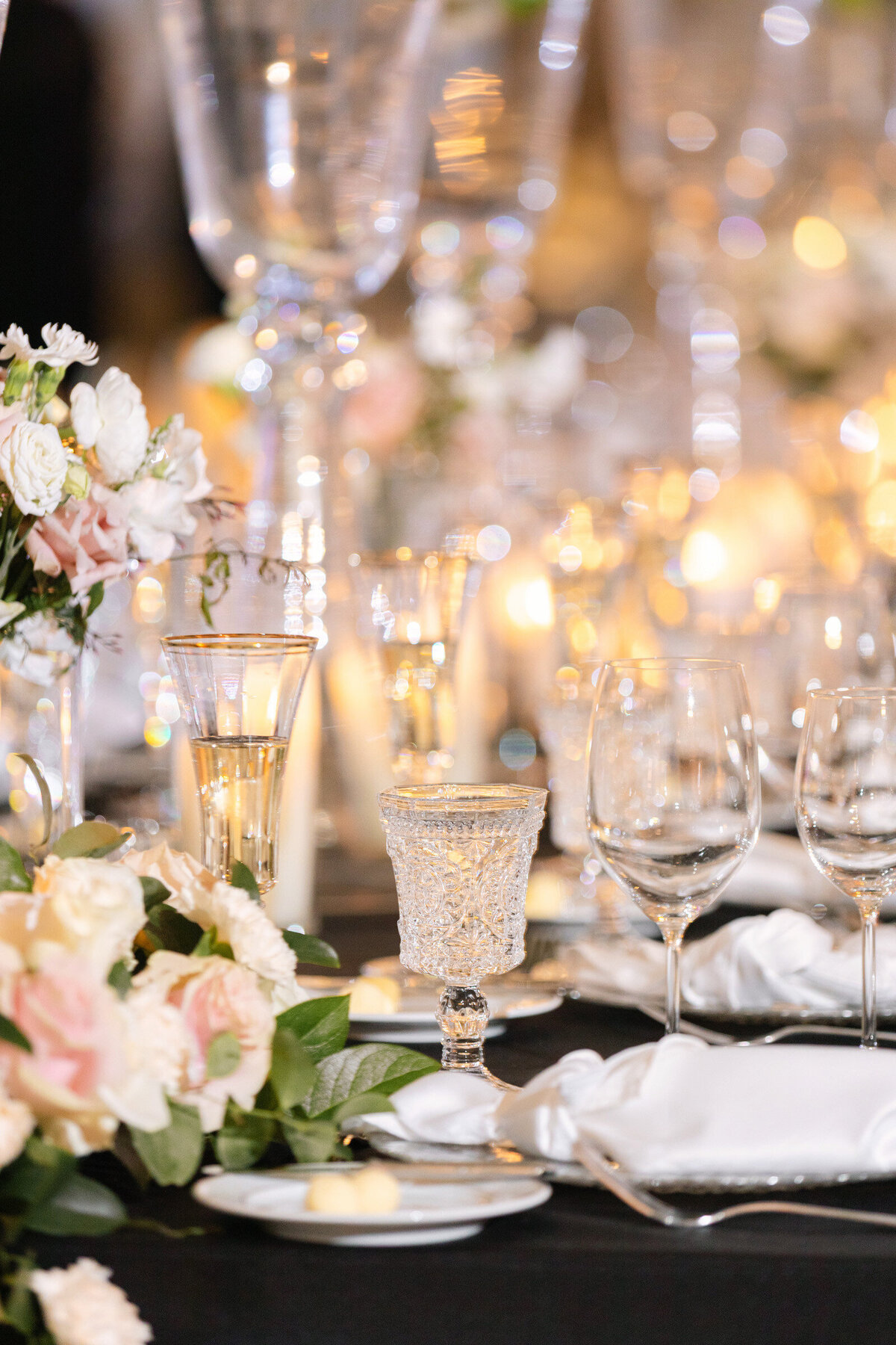 detailed shot of candles, glassware, and floral centerpieces at a wedding reception in The Adolphus in Dallas, showcasing elegant table styling.