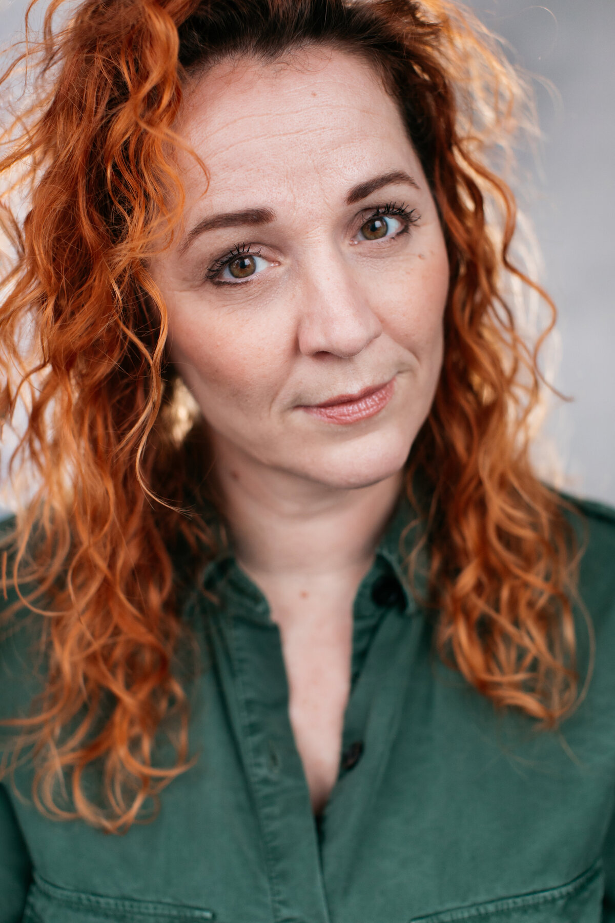 Castingfoto van Laura Burgmans. Vrouw met rood krullend haar en donkergroen overhemd.