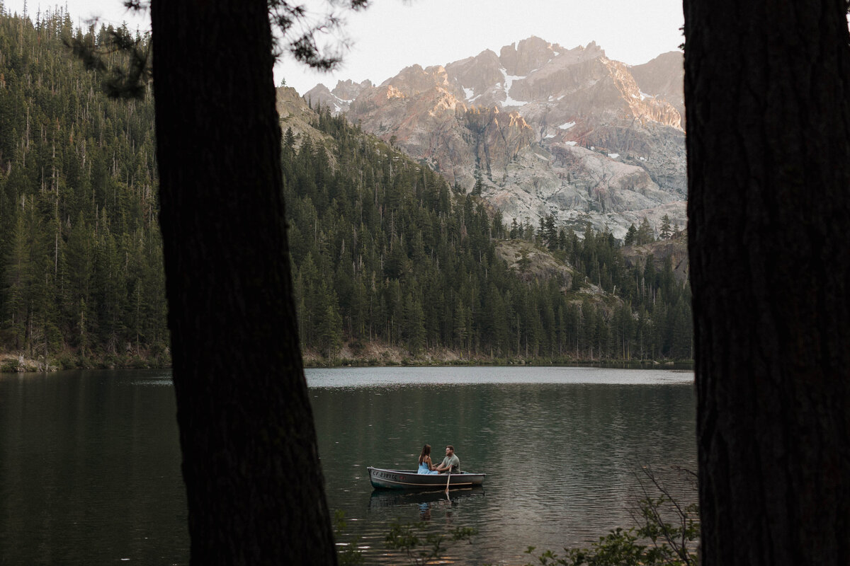 A couple captured in an intimate, cinematic moment on a boat, surrounded by mountains during their luxury documentary-style engagement photography session.