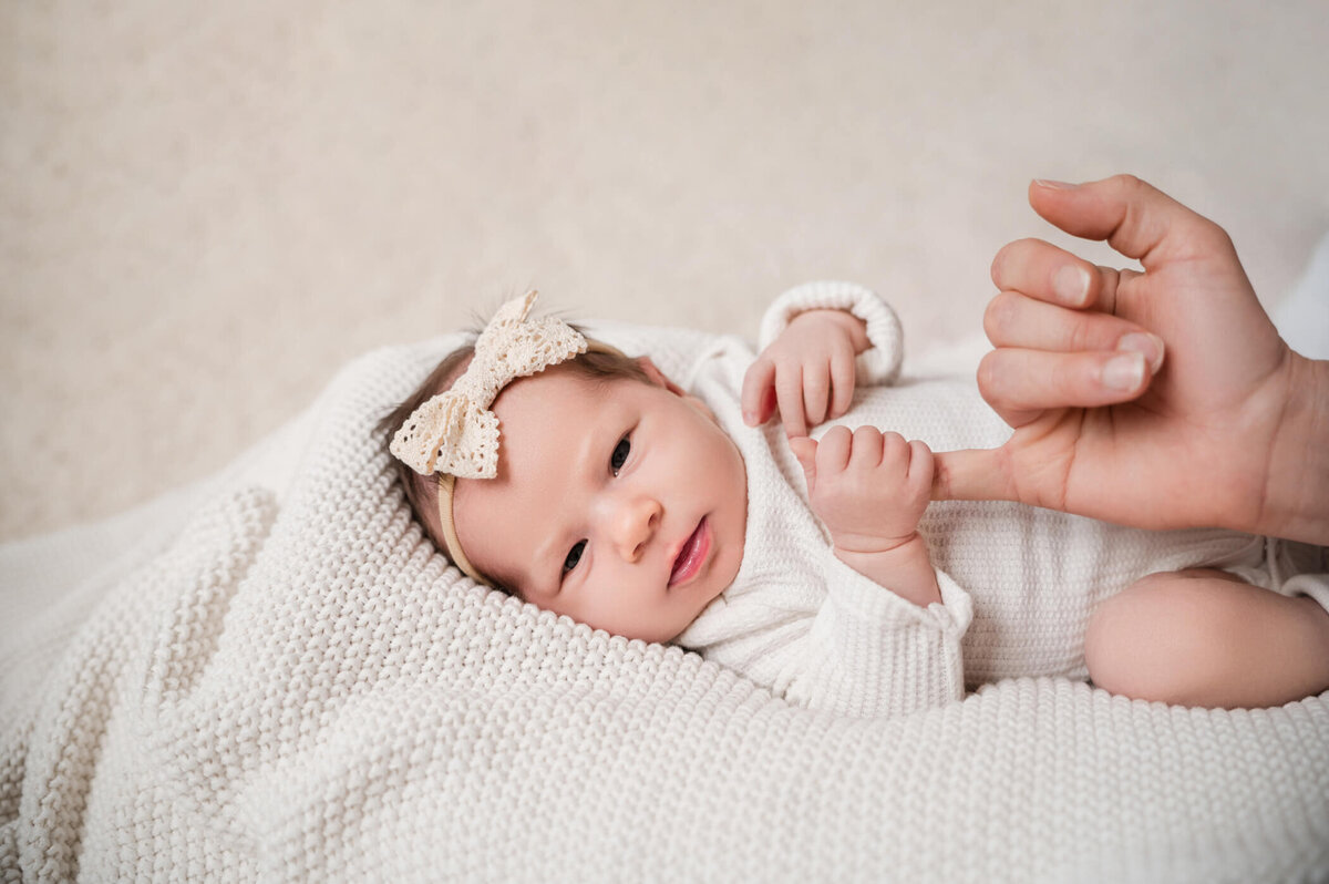 newborn looking at camera holding mom's hand