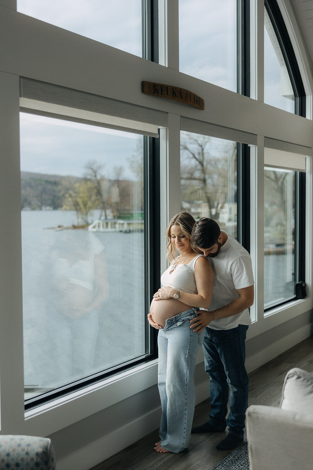 Couple standing by window at at Finger Lakes maternity session