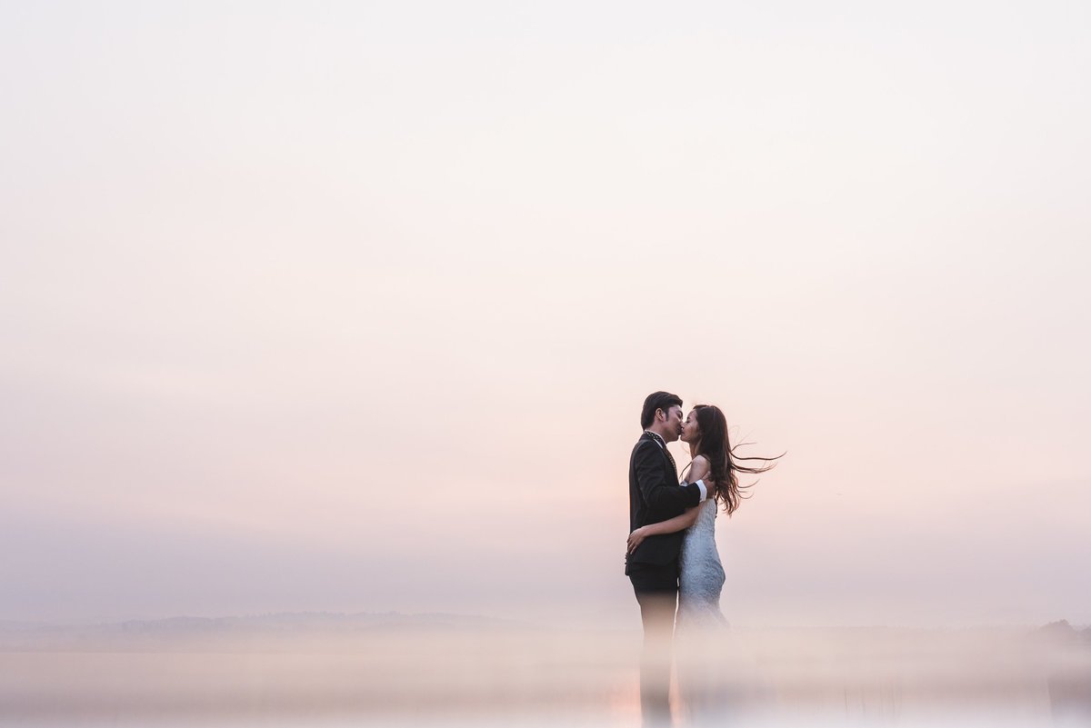 Couple kissing in front of a pink sky