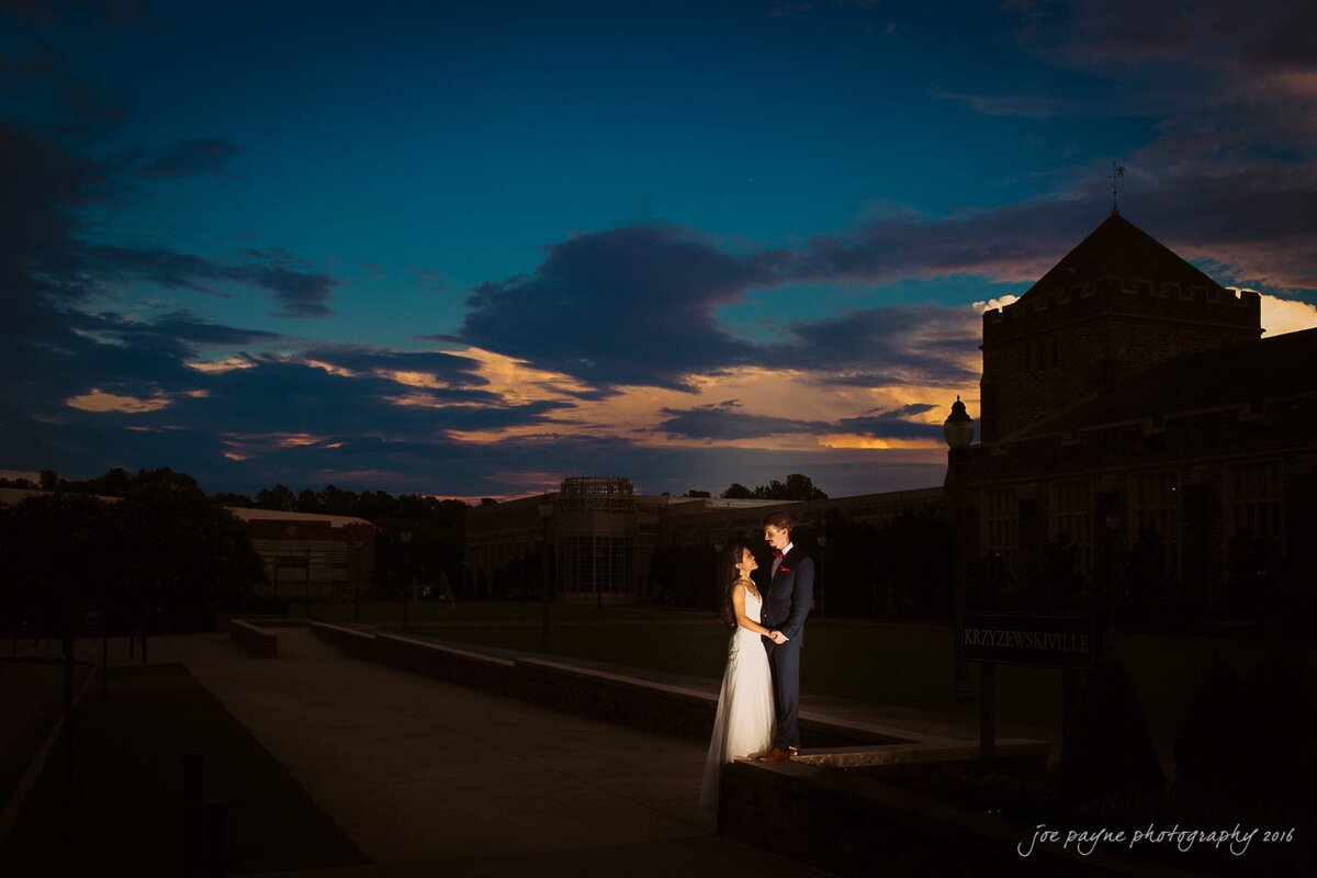 A bride and groom standing close together at sunset.