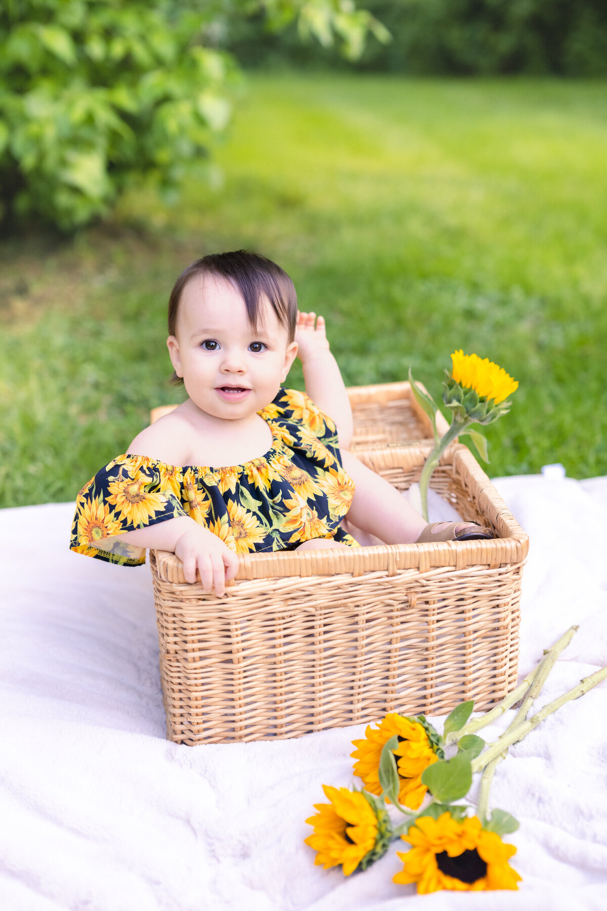 baby girl sitting in basket with sunflowers