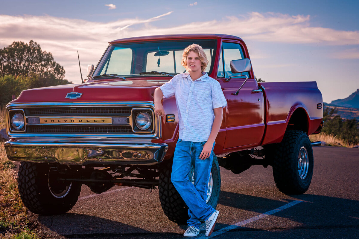 Boy poses with red vintage truck in Prescott senior photography session