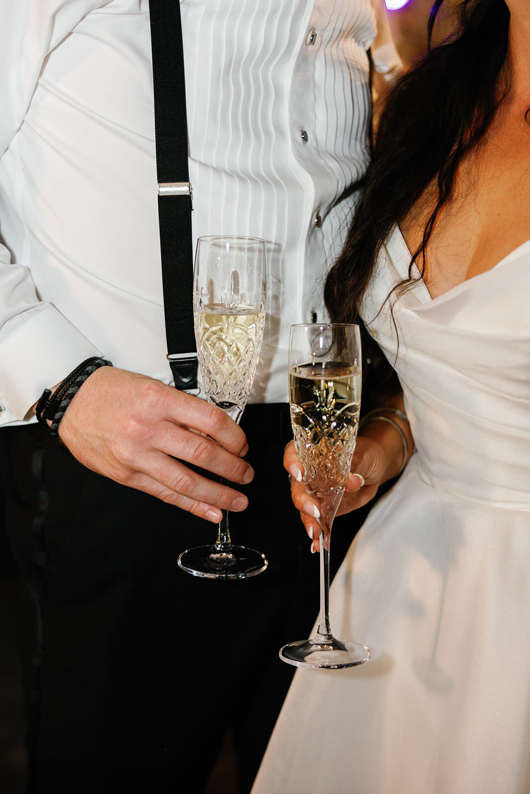 A close-up of the bride and groom's hands holding elegant champagne flutes during their wedding reception at Ocean Reef, Key Largo.