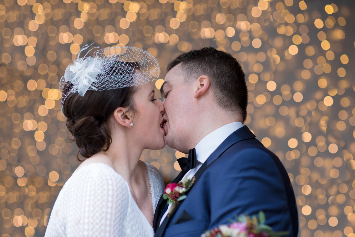 Paar küsst sich vor Lichterkette Bokeh Winterhochzeit