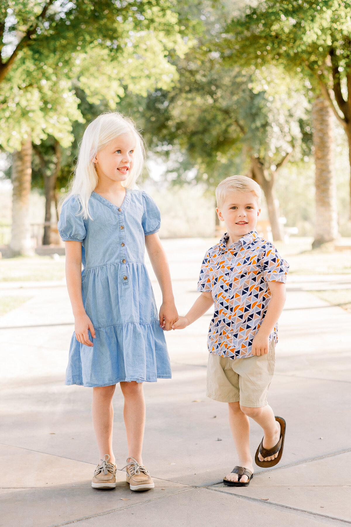 Brother and sister hold hands at park in Peoria, Arizona.