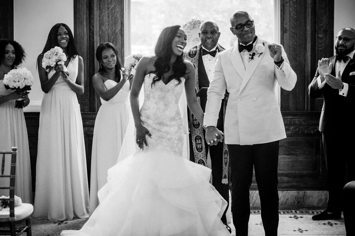 A wedding couple holding hands and celebrating after getting married.