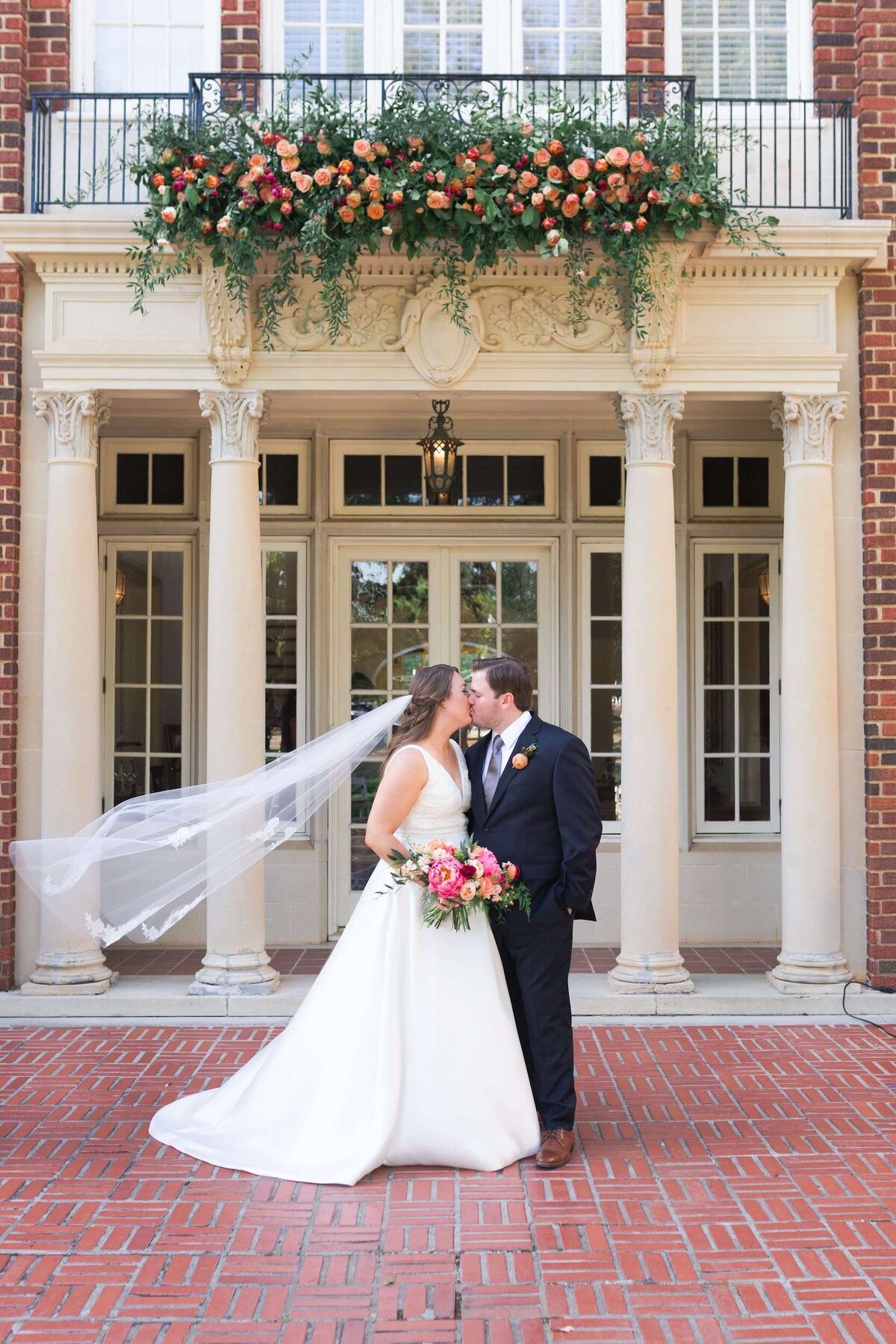 bride and groom kiss on their wedding day under cascading flowers at Astin Mansion in Houston Texas by Swish and Click Photography