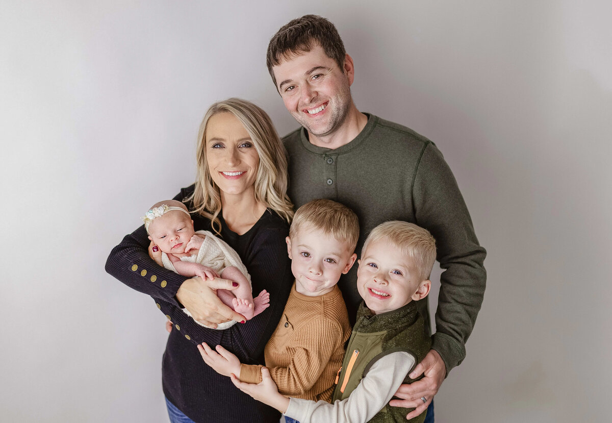 Mom and dad holding three children, including newborn - cozy family photo in Maple Grove