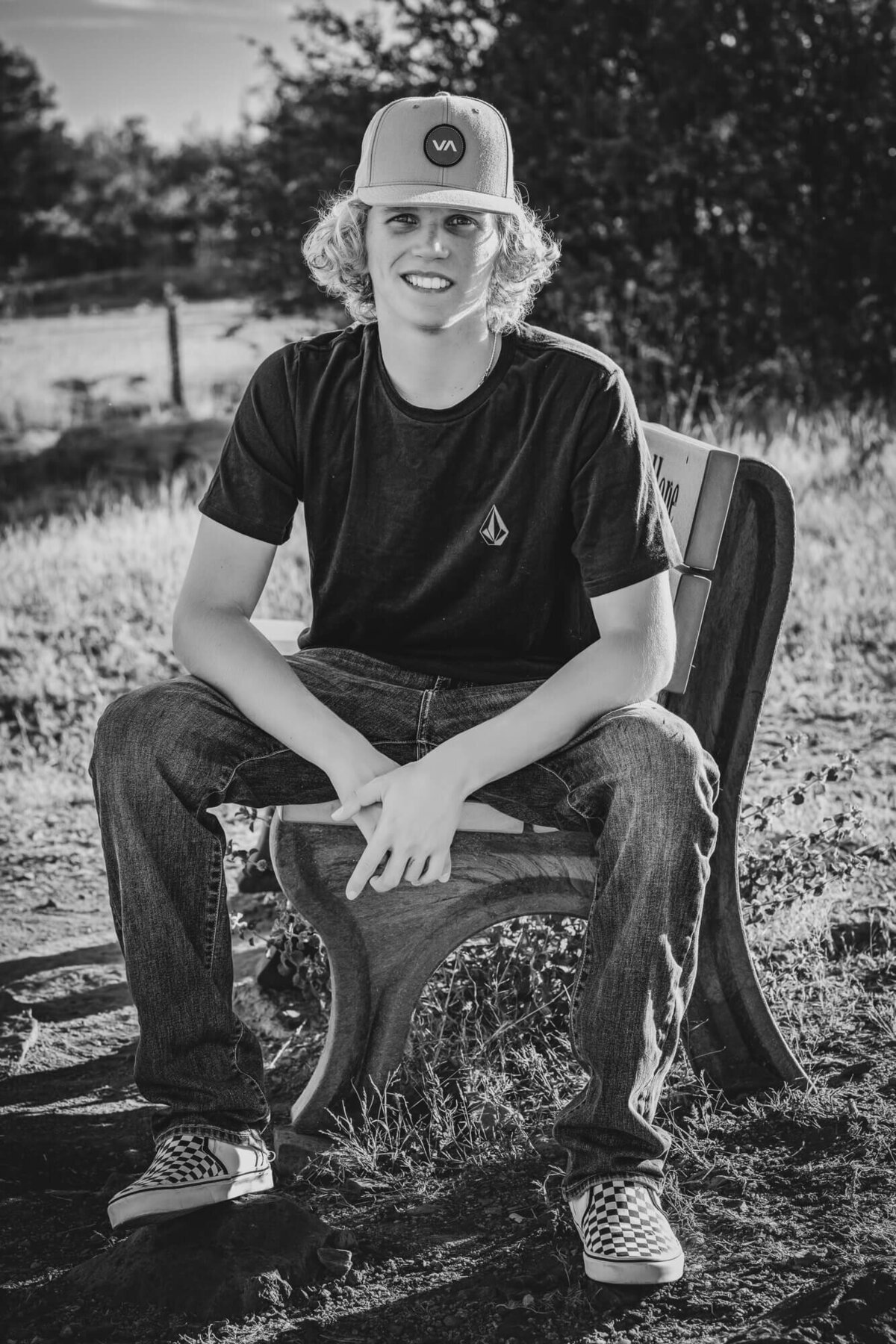 Boy poses on bench in trucker hat for Prescott senior photography session