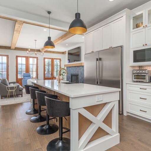 A large kitchen looking out into the living area with a center island and bar stools