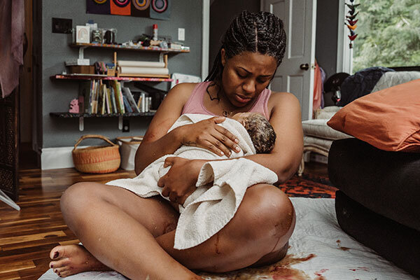 Mother holds her newborn baby in her living room at her home birth in Portland