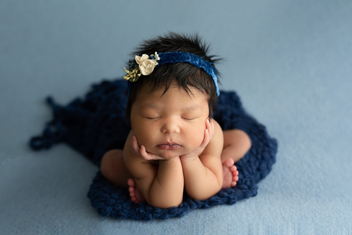 best-columbus-and-dayton-ohio-newborn-photographer-baby-girl-with-head-in-hands-on-navy-blue-with-navy-blue-headband