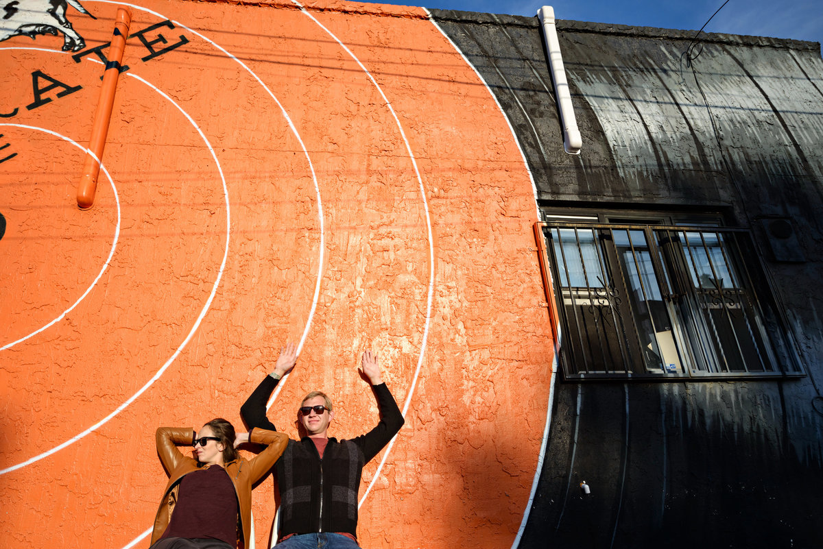 A cool couple leans agains a giant mural of a spinning record on the side of a cafe in Fishtown.