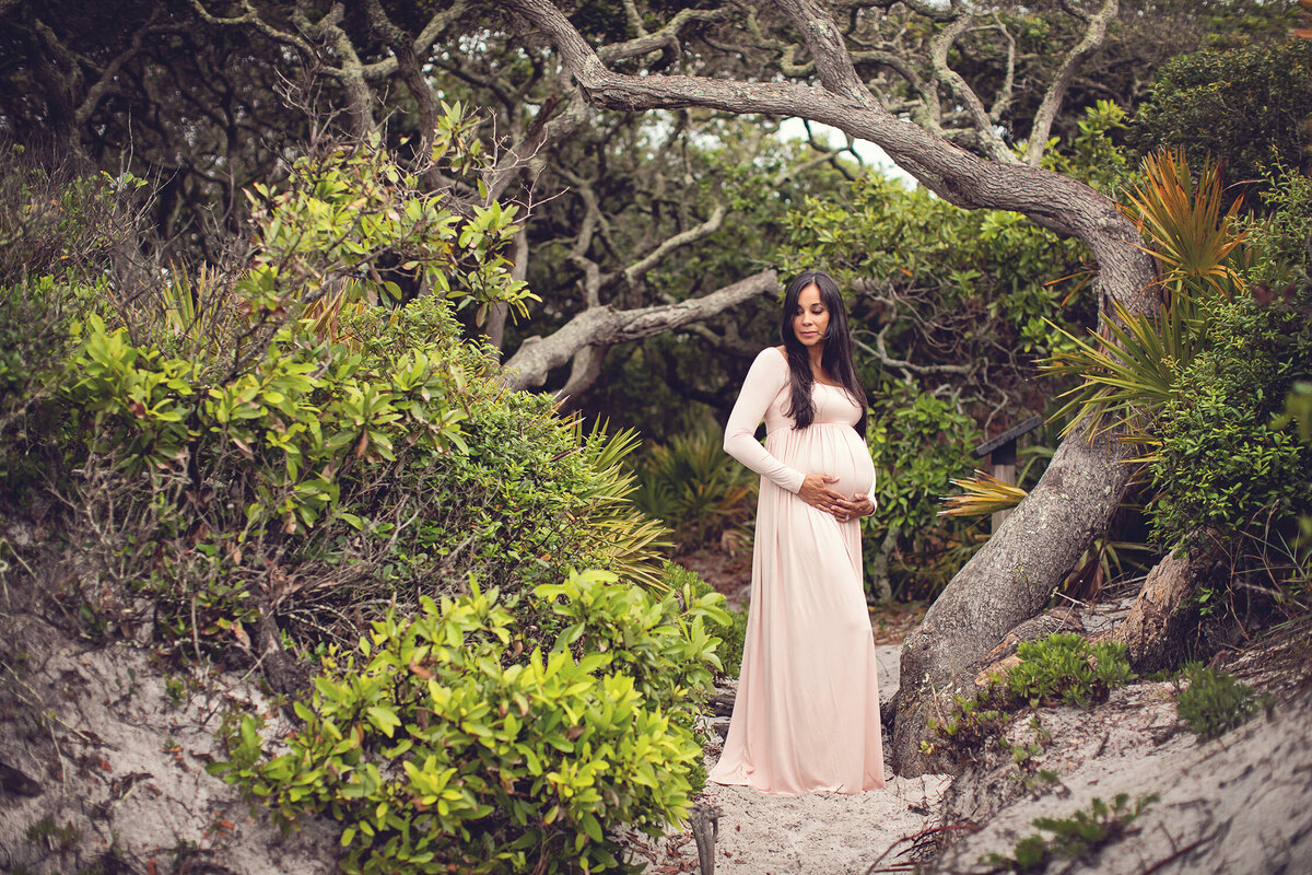 pregnant woman in pale long dress at entrance to Grayton Beach State park, FLorida.