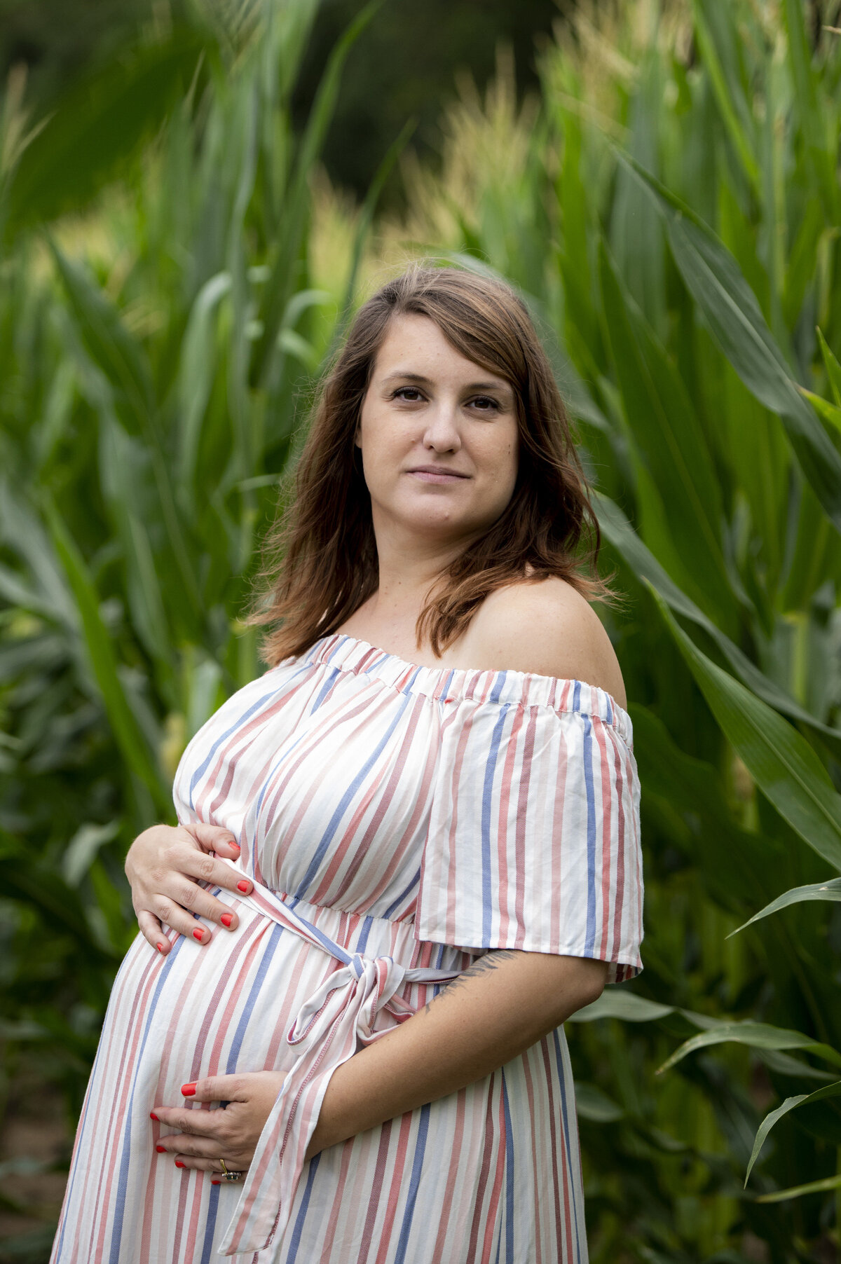 A pregnant person smiling with their hand on their stomach 