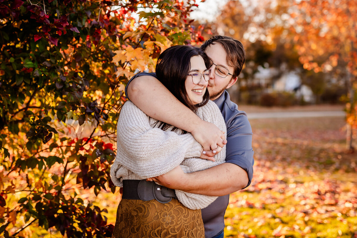 Fall engagement session with guy bear hugging girl