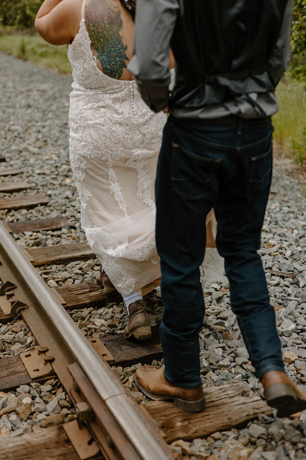 Elopement couple walks on Alaska train tracks.