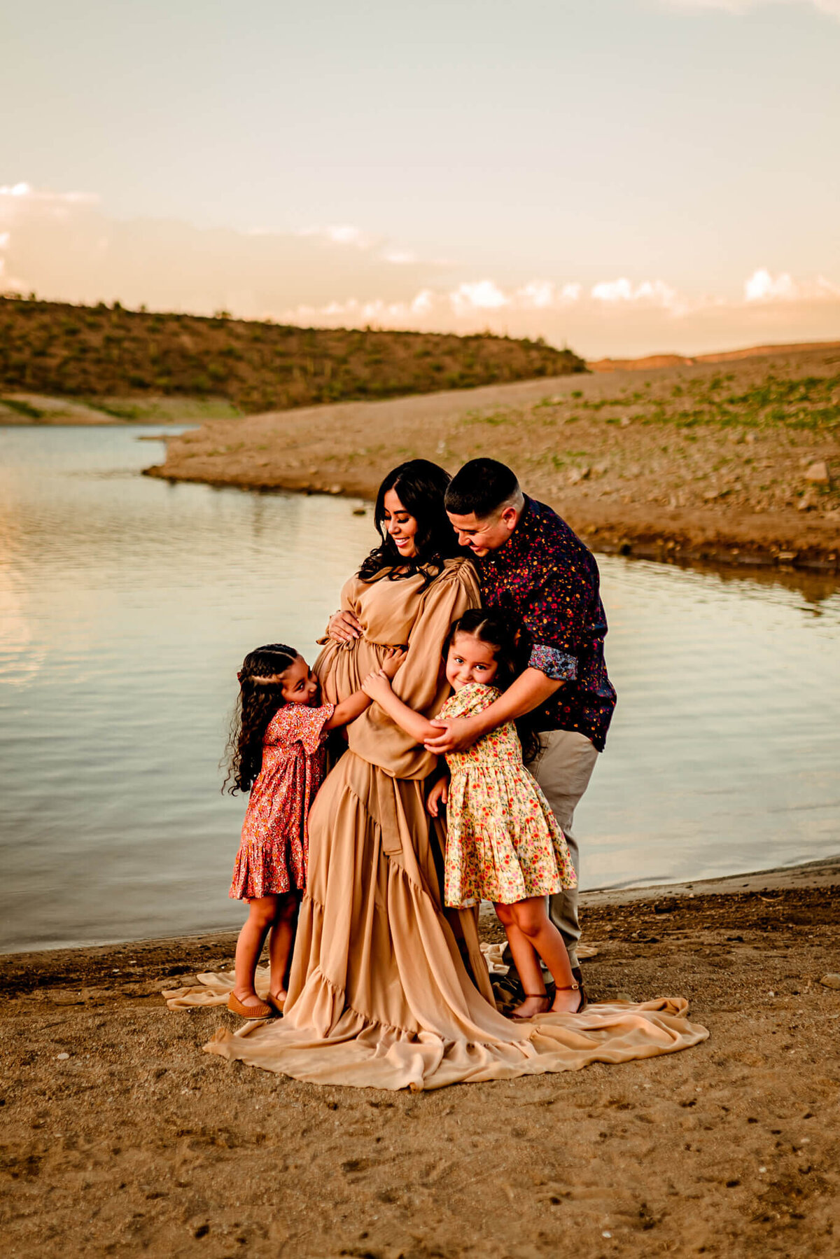 family of 4 hugging mom's belly for maternity photography session in Arizona lake
