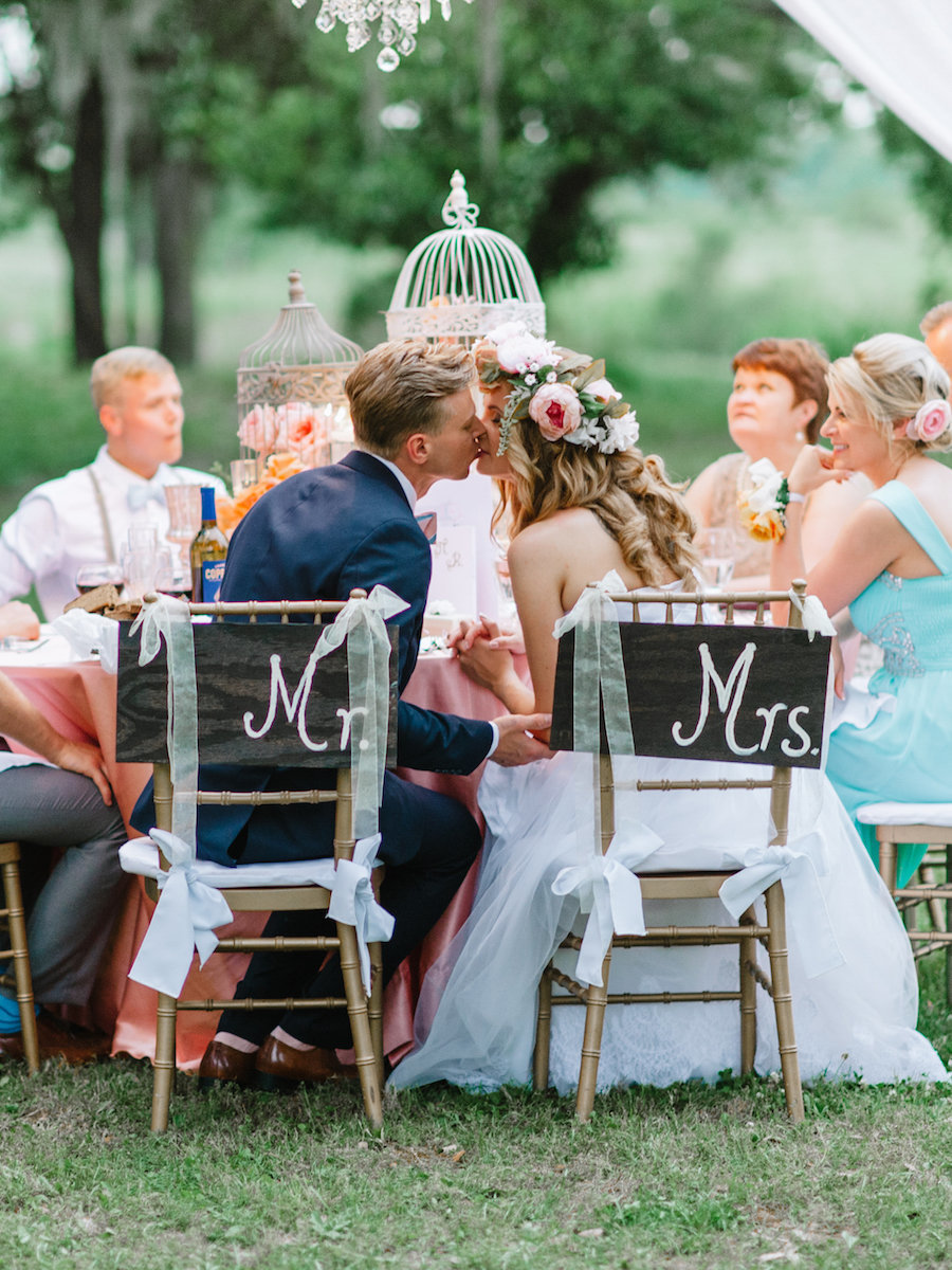 Bride and groom during an outdoor wedding ceremony in Charleston, with guests dressed in blue seated in rows
