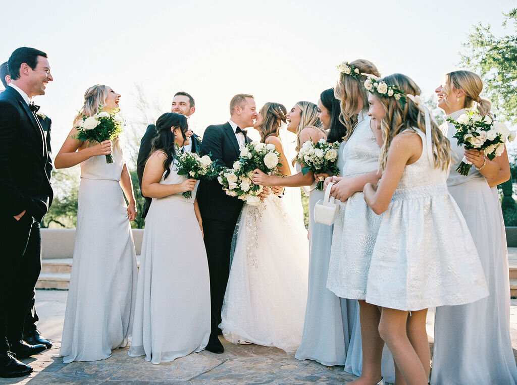 A heartwarming wedding party moment as the newlyweds celebrate with their bridesmaids and groomsmen, all dressed in elegant wedding attire.