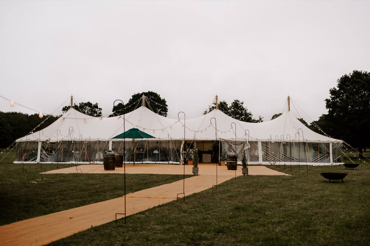 A long walkway with strings of light all the way down leading to a large pole marquee