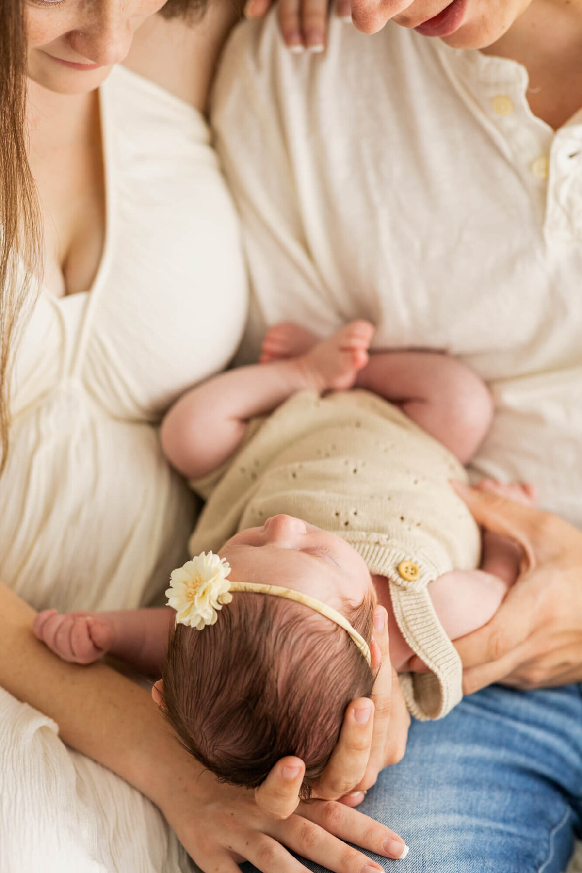 Newborn baby girl in a cream bubble in mom and dad's arms